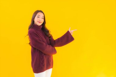 Güzel Asyalı kadın gülümsüyor. Sarı izole edilmiş arka planda başka bir eylemde mutlu.