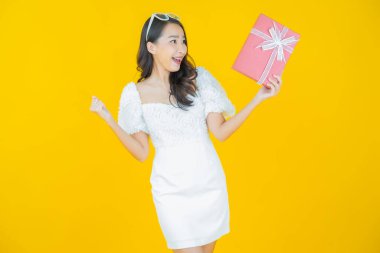 Güzel bir Asyalı kadının portresi. Arka planda kırmızı hediye kutusuyla gülümsüyor.