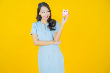 Renkli arka planda domuz kumbarası olan güzel Asyalı kadın portresi