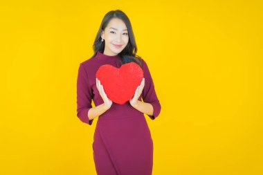 Portre güzel Asyalı genç kadın gülümsüyor kalp yastığı şeklinde renk arkaplan