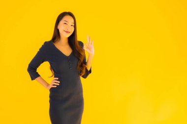 İzole edilmiş sarı arka planda hareketli güzel Asyalı kadın portresi.