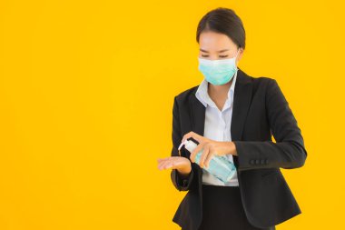 Güzel bir iş kadını portresi. Maske takıyor. Korunmak için alkol jeli kullanıyor.