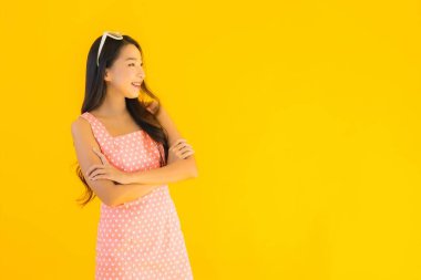 Güzel bir Asyalı kadın gülümsüyor. Sarı izole edilmiş arka planda mutlu.