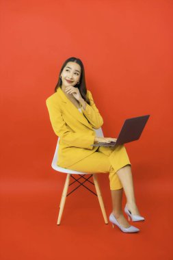 Portre güzel genç iş kadını Asyalı kadın kırmızı arka planda bilgisayar bilgisayarı kullanıyor