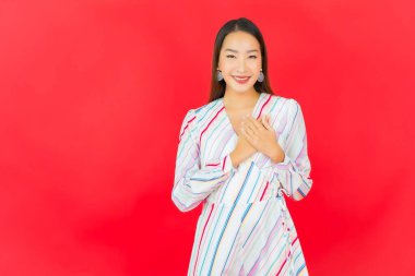 Güzel bir Asyalı kadının portresi kırmızı arka planda birçok hareketle gülümsüyor.