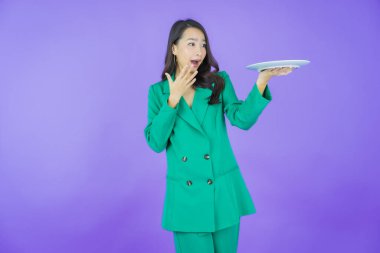 Güzel Asyalı bir kadının portresi. Arka planda boş tabak tabağıyla gülümsüyor.