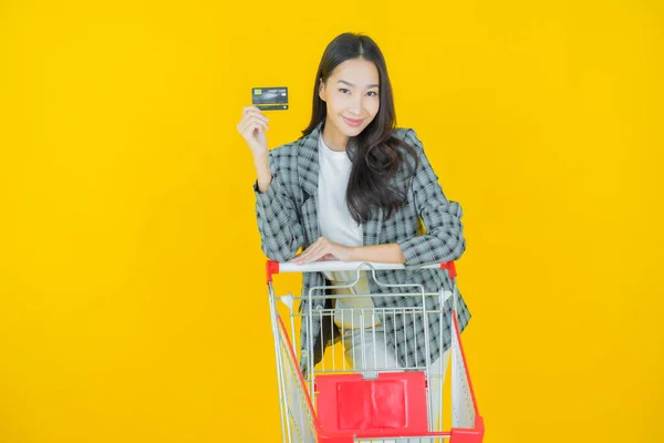 肖像画美しい若いアジアの女性は色の背景にスーパーマーケットからの食料品バスケットと笑顔 — ストック写真