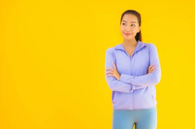 Sarı izole edilmiş arka planda spor giysili güzel Asyalı kadın portresi egzersize hazır.