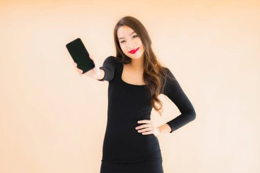 Güzel Asyalı genç bir kadının portresi mutlu bir şekilde gülümsüyor renkli arka planda akıllı cep telefonu kullan