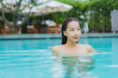 Güzel bir Asyalı kadın portresi. Rahat bir tatil için otel havuzunda yüzme havuzu etrafında gülümse.
