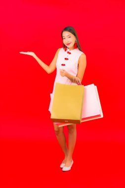 Kırmızı izole edilmiş arka planda renkli alışveriş çantalı güzel Asyalı kadın portresi.