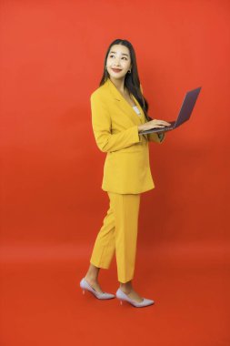Portre güzel genç iş kadını Asyalı kadın kırmızı arka planda bilgisayar bilgisayarı kullanıyor