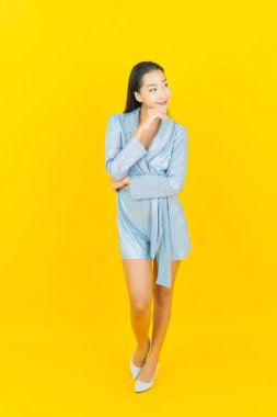 Asyalı güzel bir kadının portresi. Sarı arka planda hareketli gülümsüyor.