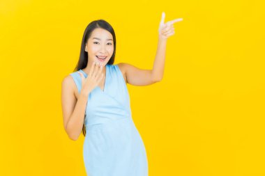 Asyalı güzel bir kadının portresi. Sarı arka planda hareketli gülümsüyor.