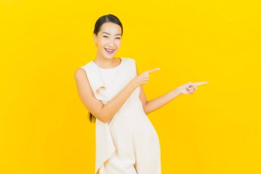 Asyalı güzel bir kadının portresi. Sarı arka planda hareketli gülümsüyor.