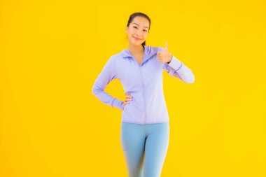 Sarı izole edilmiş arka planda spor giysili güzel Asyalı kadın portresi egzersize hazır.