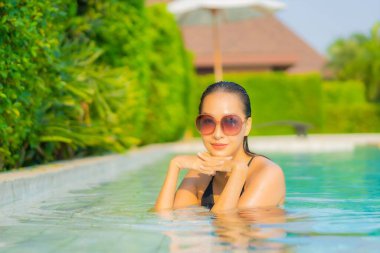 Güzel bir Asyalı kadın portresi. Rahatlayın, gülümseyin. Tatil için oteldeki yüzme havuzunun keyfini çıkarın.