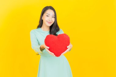 Portre güzel Asyalı genç kadın gülümsüyor kalp yastığı şeklinde renk arkaplan