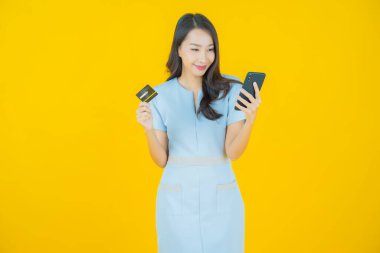 Güzel bir Asyalı kadının portresi. Renkli kredi kartıyla gülüyor.