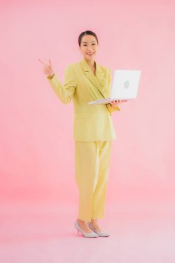 Güzel Asyalı iş kadını portresi renk arkaplanda bilgisayar bilgisayarı kullanıyor