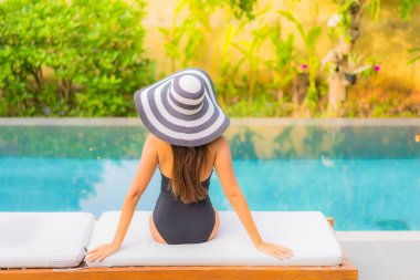 Güzel bir Asyalı kadının portresi tatil için yüzme havuzunda rahatlıyor.