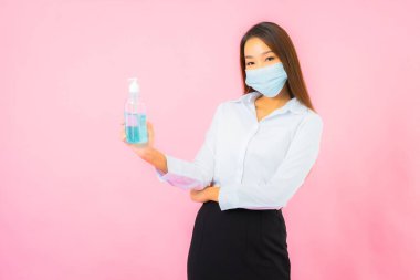 Güzel Asyalı bir kadının portresi, pembe arka planda Covid19 ve Coronavirus 'tan korunmak için maske takar.