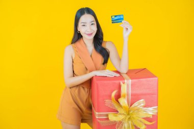 Güzel bir Asyalı kadının portresi. Arka planda kırmızı hediye kutusuyla gülümsüyor.