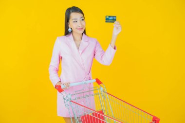 Renkli arka planda süpermarketten alınmış market sepetiyle gülümseyen güzel Asyalı kadın portresi.