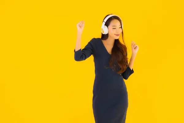 Portret Pięknej Młodej Azjatyckiej Kobiety Słuchawką Słuchania Muzyki Żółtym Odizolowanym — Zdjęcie stockowe