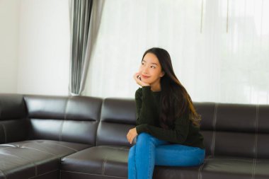 Güzel bir portre. Genç Asyalı kadın. Oturma odasındaki kanepede rahatla.