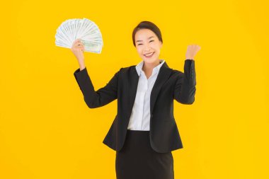 Sarıya boyanmış arka planda bir sürü nakit parası olan güzel bir Asyalı kadın portresi.