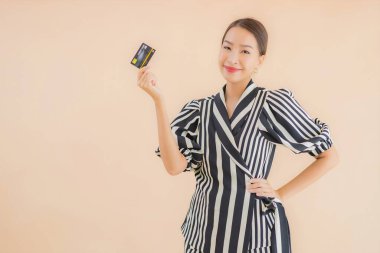 Kahverengi arka planda akıllı cep telefonlu güzel Asyalı kadın portresi.