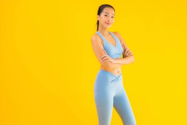 Sarı izole edilmiş arka planda spor giysili güzel Asyalı kadın portresi egzersize hazır.