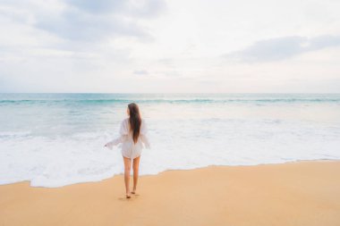 Güzel bir Asyalı kadın portresi deniz kenarında tatil yaparken rahatlar.