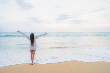Güzel bir Asyalı kadın portresi deniz kenarında tatil yaparken rahatlar.