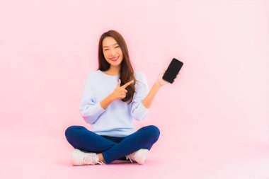 Portrait beautiful young asian woman use smart mobile phone on pink color isolated background