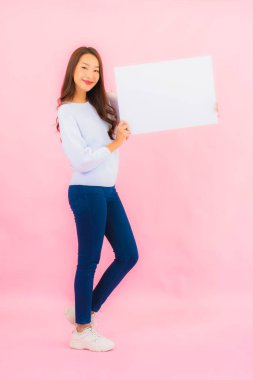 Portrait beautiful young asian woman show empty white billboard for text on pink color background