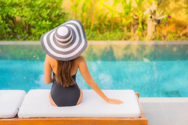 Güzel bir Asyalı kadının portresi tatil için yüzme havuzunda rahatlıyor.