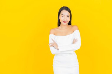 Portre güzel genç iş kadını gülümseyen ve eylem sarı arka planlı Asyalı kadın