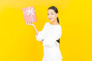 Güzel bir Asyalı kadının portresi. Arka planda kırmızı hediye kutusuyla gülümsüyor.