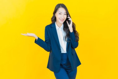 Renkli arka planda akıllı cep telefonuyla güzel Asyalı kadın gülümsemesi