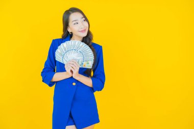 Asyalı güzel bir kadının portresi. Renkli arka planda bol para ve parayla gülümsüyor.