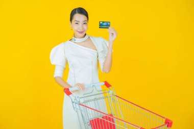 Renkli arka planda süpermarketten alınmış market sepetiyle gülümseyen güzel Asyalı kadın portresi.