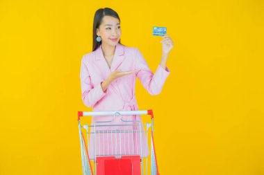 Renkli arka planda süpermarketten alınmış market sepetiyle gülümseyen güzel Asyalı kadın portresi.