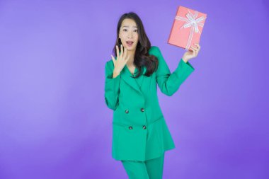 Güzel bir Asyalı kadının portresi. Arka planda kırmızı hediye kutusuyla gülümsüyor.