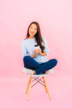 Portrait beautiful young asian woman sit on chair with pink color background