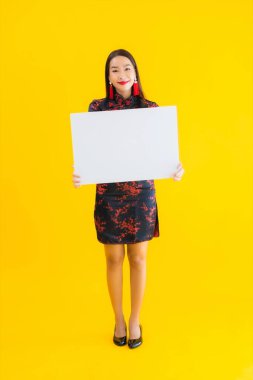 Güzel bir Asyalı kadın portresi, Çin 'de yeni yıl konsepti olarak sarı izole edilmiş arka plan üzerine beyaz boş ilan panosu giyiyor.