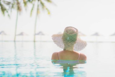 Güzel bir Asyalı kadın portresi. Tatil gezisinde deniz manzaralı açık havuz etrafında rahatça yüzebiliyor.