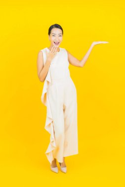Asyalı güzel bir kadının portresi. Sarı arka planda hareketli gülümsüyor.