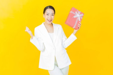 Güzel bir Asyalı kadının portresi. Arka planda kırmızı hediye kutusuyla gülümsüyor.